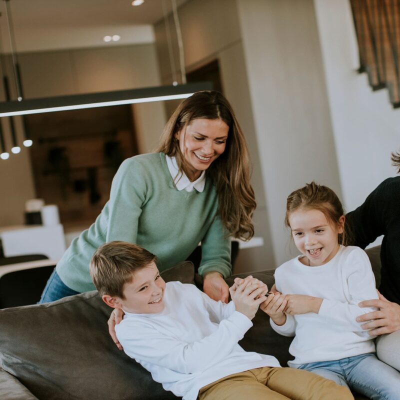genitori felici con bambini sul divano di casa